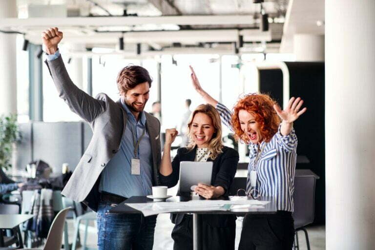 A group of business people standing in an office, expressing excitement