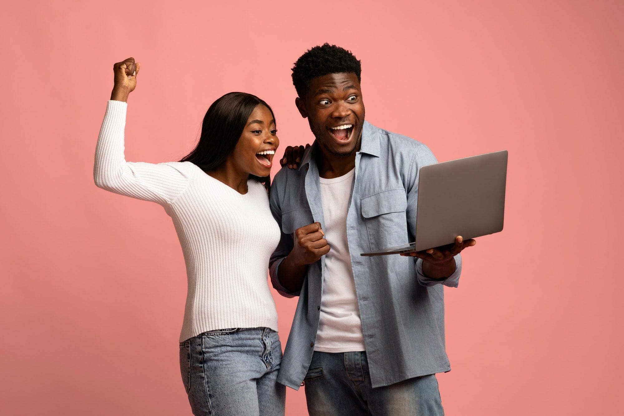 Excited black couple celebrating win with laptop