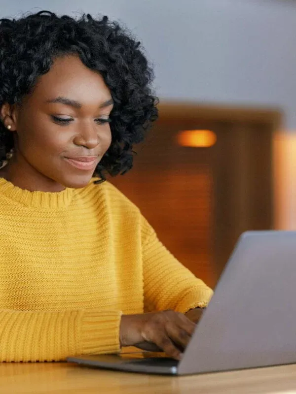 Young businesswoman typing email on laptop, sitting at cafe